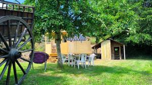 a table and chairs under a tree in a yard at La Roulotte Cacahuète in Pont-d'Ouilly