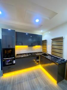 a kitchen with black cabinets and yellow lighting at Heritage Apartment in Ibadan