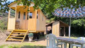 a wooden play house with a bench and a table at La Roulotte Cacahuète in Pont-d'Ouilly