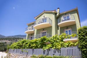 a green building with balconies and a fence at Nikos & Vassilis apartments Kefalonia in Vlachata