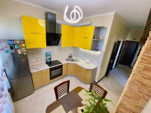 a kitchen with yellow cabinets and a table and a sink at Марсельская Residence in Kryzhanivka
