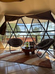 two chairs and a table in a room with windows at Glamping Cabañas Luz y Vida in Chignahuapan