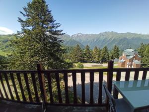 a balcony with a table and a tree and mountains at Profitez de la vue in Ustou