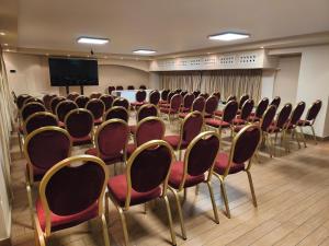 ein Konferenzraum mit Stühlen, einem Tisch und einer Leinwand in der Unterkunft Hotel Iliana in Filippiada