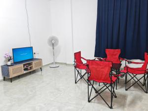 a room with red chairs and a table and a tv at Tetiba Suite in Muar
