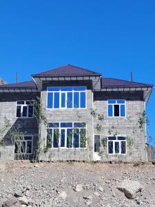 a brick house with blue windows on a field at Nofin Lake House in Panjakent