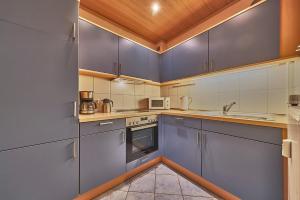 a large kitchen with blue cabinets and appliances at Haus Schildt, FeWo 7 in Duhnen