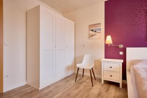 a bedroom with a white closet and a white chair at Haus Schildt, FeWo 7 in Duhnen