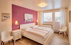 a bedroom with a white bed and a purple wall at Haus Schildt, FeWo 7 in Duhnen