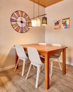 a dining room table with white chairs and a clock at Haus Schildt, FeWo 7 in Duhnen