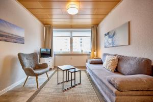 a living room with a couch and a chair at Haus Schildt, FeWo 7 in Duhnen +9 photos