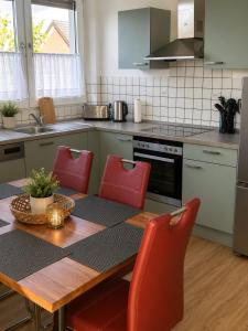 a kitchen with a wooden table and red chairs at FeWo Auszeit eigene große Terrasse mit Strandkorb und Grill in Wesel