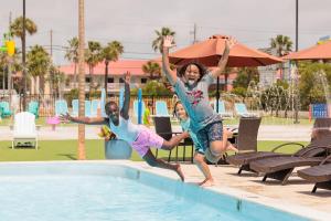 zwei junge Mädchen springen in ein Schwimmbecken in der Unterkunft Hotel Tybee in Tybee Island