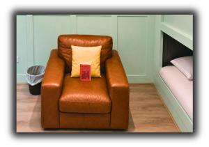 a brown leather chair with a pillow in a room at Pitchside Rooms in Liverpool