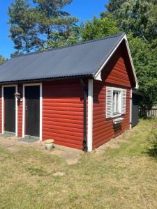 a red shed with a black roof at Röda huset in Åhus +1 photo