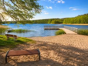 a bench on the shore of a lake with a dock at Wiśniowa Chata in Rentyny +5 photos