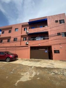 a red building with a car parked in front of it at Djess service in Abidjan