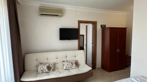 a living room with a white couch and a tv at Yağmur Apart Otel in Didim