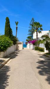an empty street with palm trees and the ocean at Villa Bleu Horizon in El Haouach