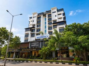 a tall white building with trees in front of it at Hotel Kings Residency Panvel in Navi Mumbai