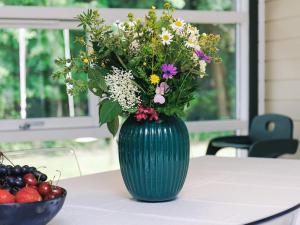 a green vase with flowers on a table next to a bowl of fruit at 4 star holiday home in Væggerløse in Bøtø By