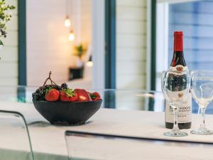 a bottle of wine and a bowl of fruit on a table at 4 star holiday home in Væggerløse in Bøtø By +43 photos