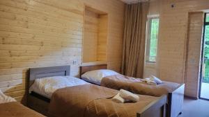 two beds in a room with wooden walls at Guest House Adelina in Mestia