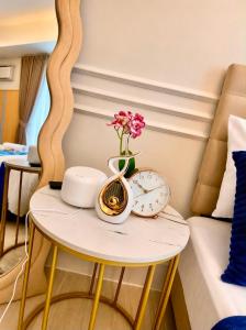 a table with a clock and a vase with flowers on it at Yssabelle's Homestay in Sampong +2 photos