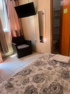 a bedroom with a bed and a chair and a mirror at Hotel El Huacachinero- Hotel Familiar in Ica
