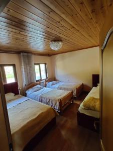 three beds in a room with wooden ceilings at Guest House Trojani in Lëpushë