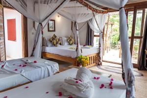 two beds in a room with flowers on the floor at Tunu Beach Zanzibar in Kizimkazi