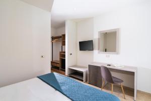 a bedroom with a bed and a desk and a chair at Matala Bay Hotel in Matala