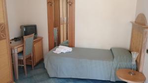 a bedroom with a bed and a desk and a television at Hotel Tre Lanterne in Marina di Sibari