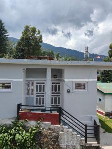 a white house with a porch and stairs in front of it at MP Residency Homestay in Munsyari
