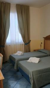 two beds in a room with a window at Hotel Tre Lanterne in Marina di Sibari