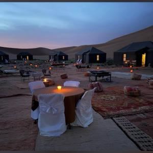 a table and chairs in the middle of the desert at Erg Chigaga Luxury Camp in El Gouera