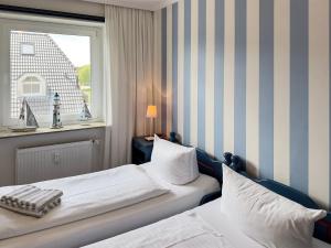 a hotel room with two beds and a window at Ferienwohnung *Jessen´s Wattblick* in Wittdün