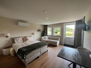 ein Schlafzimmer mit einem Bett, einer Couch und einem Tisch in der Unterkunft De Brummelstee in Beilen