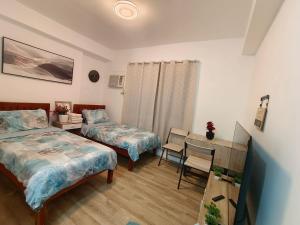 a bedroom with two beds and a desk and a table at Hailey's Place Unit 3 in Bacolod +10 photos
