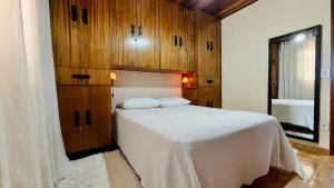 a bedroom with a white bed and wooden cabinets at Recanto Luar Monte Verde in Monte Verde +13 photos