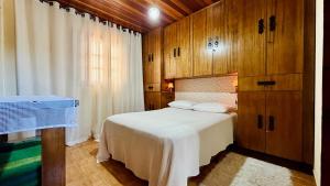 a bedroom with a bed with wooden walls and a window at Recanto Luar Monte Verde in Monte Verde