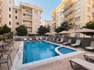 a swimming pool with chairs and tables and buildings at Livane Beach Hotel in Alanya