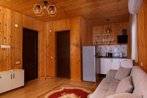 a kitchen and a living room with wooden walls at Sky Glass Cottage in Kʼveda Chʼkhutunetʼi +12 photos