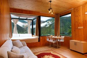 a living room with a couch and a large window at Sky Glass Cottage in Kʼveda Chʼkhutunetʼi