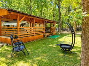 a cabin with two chairs and a swing in the yard at Chatka w środku lasu in Czerwona Wola