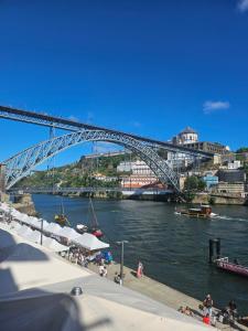 a bridge over a river with people on a dock at Muralha da Barca Apartamentos -Fique no centro do Porto junto a ponte D-Luis IRNAL nº13939 Al,5848 Al, 6419 AL-Chamada para a rede móvel nacional in Porto