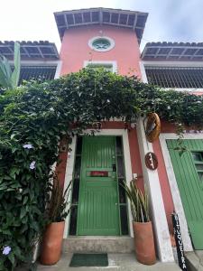 a house with a green door and some plants at Caiçara Guest House in Ubatuba