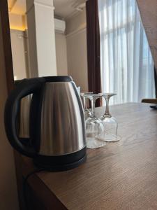 a coffee pot and glasses on a wooden table at Hotel Lux in Mitrovica