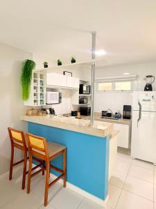 a kitchen with a blue counter and two chairs and a refrigerator at FLAT MANDAI PREMIUM - Cabo Frio in Cabo Frio
