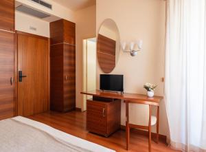 a bedroom with a desk with a tv and a mirror at Hotel Gala in Pesaro +11 photos